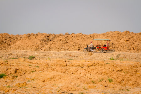 SIEMREAP, CAMBODIA - MARCH 14 2013: a man rides a motorcycle along the Tonlesap Riverのeditorial素材