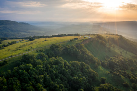 Early morning in the mountains. Morning sun and haze in the valley against the background of...