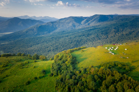 Early morning in the mountains. Morning sun and haze in the valley against the background of mountains. Tents in the mountainsの写真素材