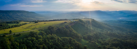 Early morning in the mountains. Morning sun and haze in the valley against the background of mountainsの写真素材