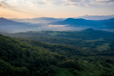 Early morning in the mountains. Morning sun and haze in the valley against the background of mountainsの写真素材