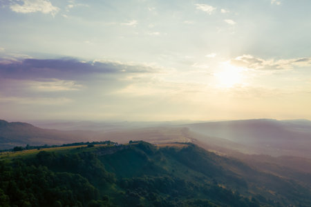 Early morning in the mountains. Morning sun and haze in the valley against the background of mountainsの写真素材