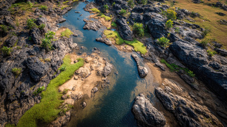 This stunning aerial photo captures a serene river winding through rocky landscapes, complemented by patches of greenery and vibrant natural beauty.の素材