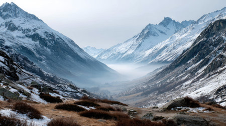 Witness a breathtaking view of snow-capped mountains enveloped in mist, showcasing the serene beauty of a winter alpine valley. An ideal escape into nature.の素材