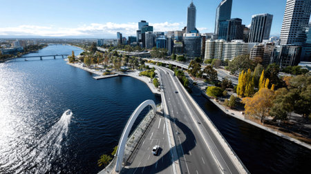 Stunning aerial view showcasing a modern city skyline alongside a river, framed by vibrant autumn foliage and serene water reflections.の素材