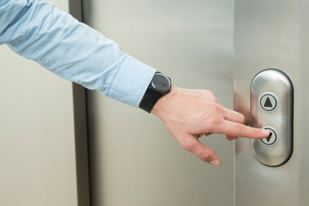 Person pushing down arrow elevator button