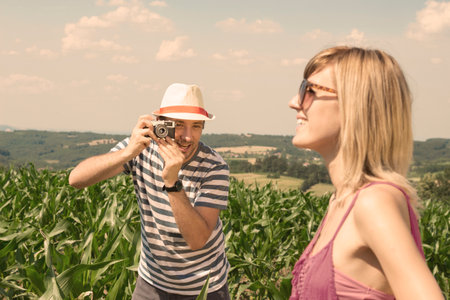 Young photographer finding the best position to take a shoot of his girlfriend outdoorの写真素材