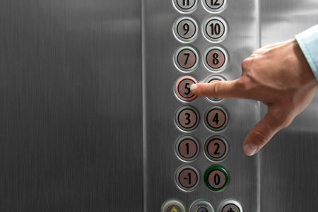 Male forefinger pressing the fifth floor button in the elevator. External flash light. Metal made...