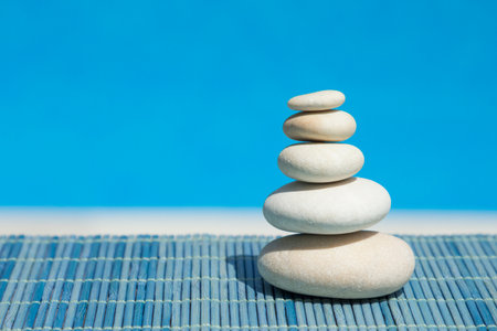 Zen stones one above the other on blue bamboo straw mat の写真素材