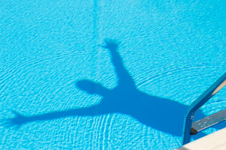 Man shadow with arms raised in the swimming poolの写真素材