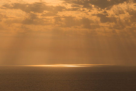 Sunrays through clouds scene. Sunlight on the sea surface.