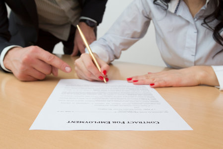 Female hands signing contract for employment. Employerâs forefinger showing the part of a document where new employee should put her signatureの写真素材
