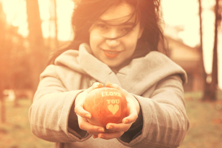 Woman holding apple with I love you inscription. Outdoors scene. Love spreading concept. の写真素材