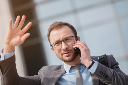Young professional in suit having a call. His right hand is raised up. の写真素材
