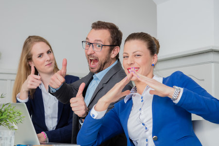 Business team members sitting at the desk and happy because another project is successfully finished. They are gesticulating with their hands in a positive way.  の写真素材