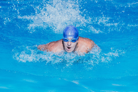 Young healthy man with muscular body swims in swimming pool and representing healthy lifestyle conceptの写真素材