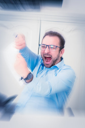 Businessman under stress, tearing paper document to pieces. He is sitting at the desk in the office.    の写真素材