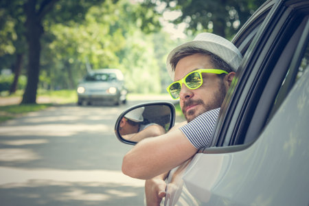 Portrait of young driver wearing sunglasses in driverâ€™s seat. Vacation and travel concepts.