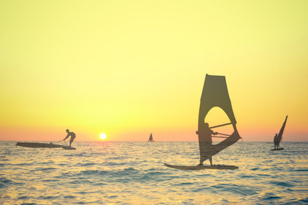 Transparent silhouettes double exposure of wind surfers on sea at the sunset. Sport, summer and vacation concepts.の写真素材