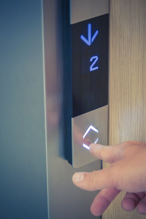 Person pushing down arrow button of modern elevatorの写真素材