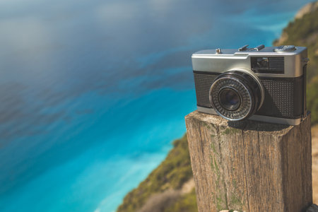 Vintage retro camera on wooden fence and beautiful turquoise sea in the background. Retro technology and summer vacation concepts. Space for copy. の写真素材