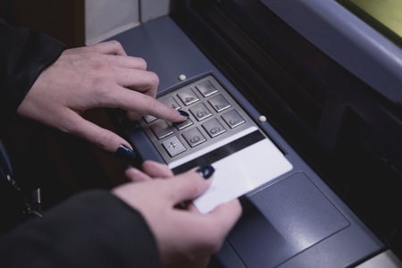 Close up of female hand holding ATM card and entering security codeの写真素材
