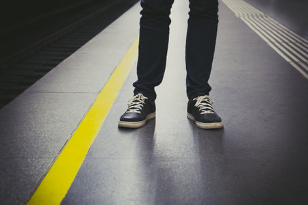 Close up of urban man feet in sneakers on subway platform. Urban life concept.
