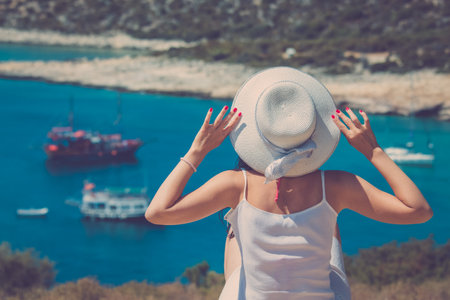 Female sitting on hill. Beautiful bay with ships in the background.の写真素材