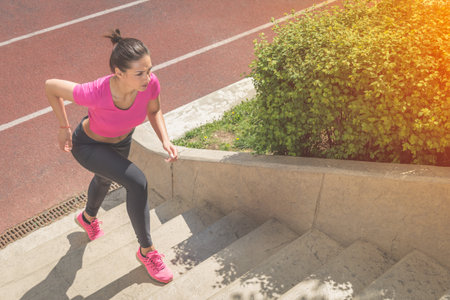 Muscular sportswoman running up on stairs. Morning workout. Urban scene. Fitness, sport, recreation,...