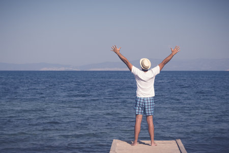 Rear view of man standing on pier by the sea.