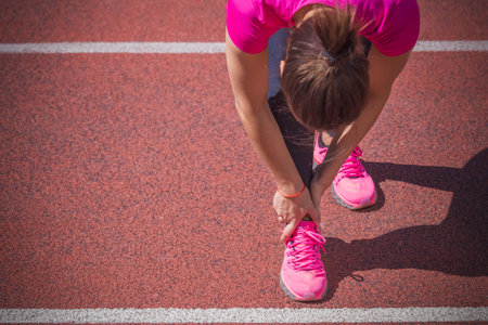 Female jogger hands on foot. She is feeling pain as her ankle or foot is broken or twisted. Accident...