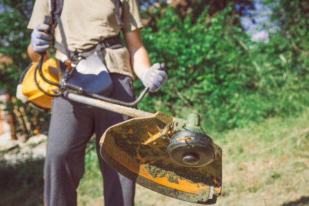 Man Mowing the Grass by using gasoline lawn trimmer 