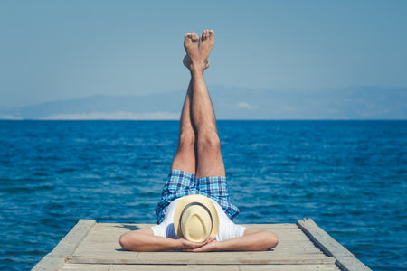 Young tourist laying on wooden pier and enjoying the sunny summer dayの写真素材