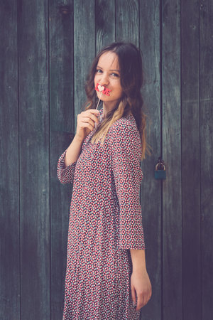Portrait of pretty young female holding love text sign on stick on wooden wall retro background. Fashion and  lifestyle concepts.の写真素材