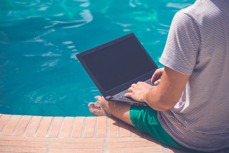 Freelancer working on vacation at the poolsideの写真素材