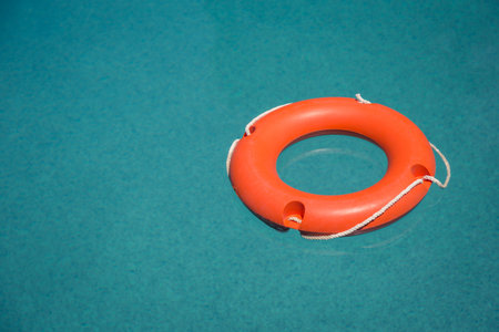 Orange lifebuoy on blue swimming pool water surfaceの写真素材
