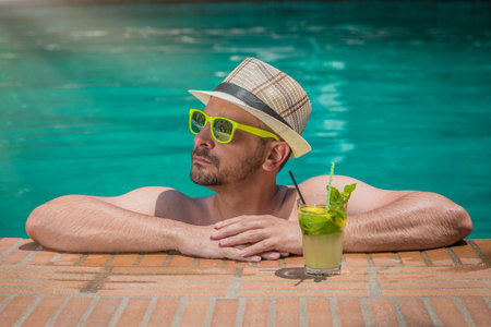 Man enjoying and relaxing in swimming pool with mojito cocktailの写真素材