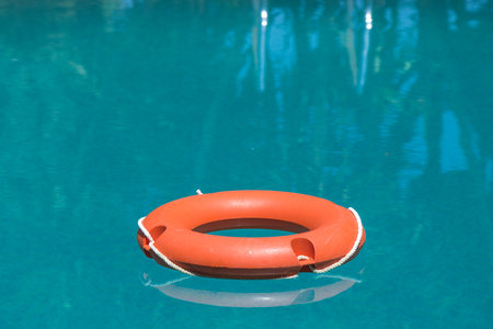 Orange lifebuoy on blue swimming pool water surfaceの写真素材