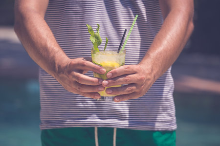 Close up of man hands holding mojito cocktail. Summer vacation and travel concepts.の写真素材
