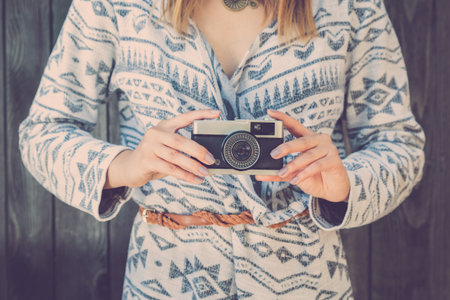 Close up of fashionable retro styled female holding vintage old film cameraの写真素材
