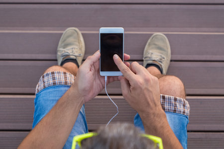 High angle view of modern urban man using blank screen smart phone against wooden floorの写真素材