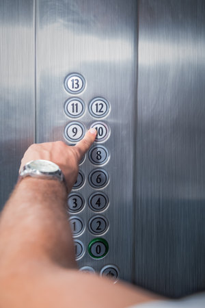 Close up of male forefinger pressing ten floor button in the elevator. Iron made interior.
