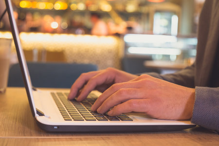A closeup of businessman using a computer keyboard in cafeの写真素材