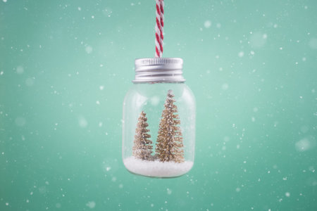 Close up of transparent decoration ornament jar with golden Christmas tree and snow in it. の写真素材