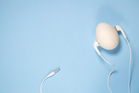White egg with earphone on pastel blue background minimal concept. Space for copy.の写真素材