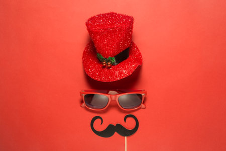 Hipster retro vintage eccentric man with red cylinder hat sunglasses and mustaches abstract against red background minimal concept.の写真素材