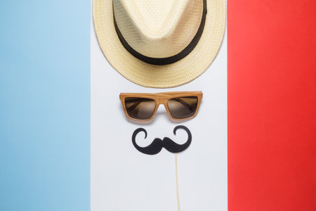Hipster retro vintage guy abstract against french flag background minimal concept. Hat, sunglasses and mustache paper prop flat lay.の写真素材