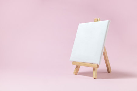Easel for artists and blank canvas miniature on pastel pink background. Art minimal concept.の写真素材