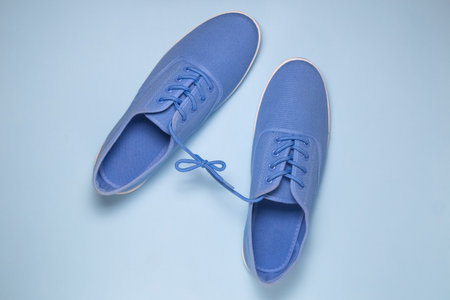 Flat lay of blue sneakers tied with shoelaces on blue pastel blue background. Minimal conceptの写真素材