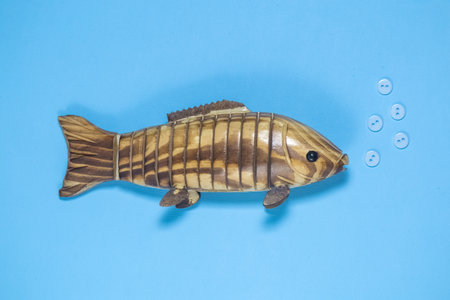 Wooden fish on blue background with air bubbles made of buttons abstract. Creative minimal concept.の写真素材